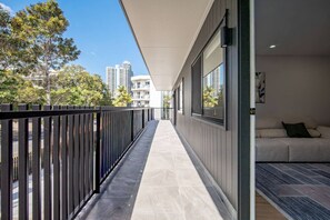 A modern apartment with a balcony, a sofa, and a view of tall buildings. - Brand-New|Walk to Cavill & Beach| Glink |Full A/C (Surfers Paradise)