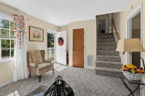 A living room with a sofa, a door, a staircase, and a fruit basket. - Near MCAS New River - Peaceful Home w Patio (Jacksonville)