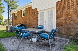 An outdoor patio with a table and chairs, a grill, and a brick wall. - Near MCAS New River - Peaceful Home w Patio (Jacksonville)