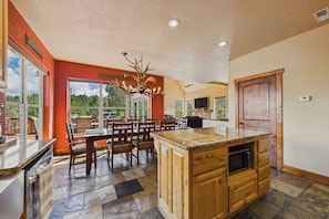 A spacious kitchen with a large island, wooden cabinets, and a chandelier. - Casa Oso Grande - Hot Tub, Deck, Fireplaces, Games (Ruidoso)