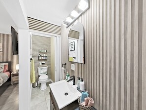 Casa de banho moderna com um espelho grande, uma sanita branca e decoração de parede riscada.