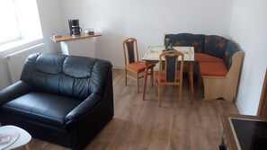Un soggiorno con un divano in pelle nera, un tavolo da pranzo in legno con sedie e un divano colorato.