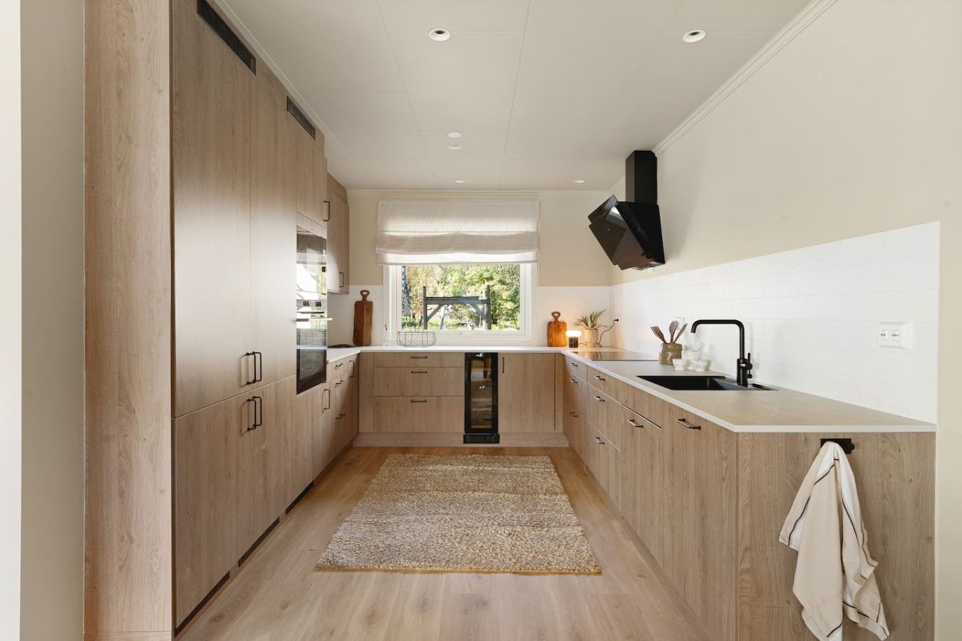 Une cuisine moderne avec des meubles en bois, un îlot central et une fenêtre qui laisse entrer la lumière naturelle.
