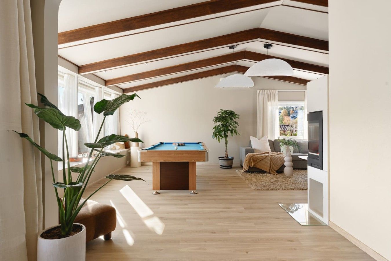 A spacious living area with a pool table, wooden beams, and large windows.