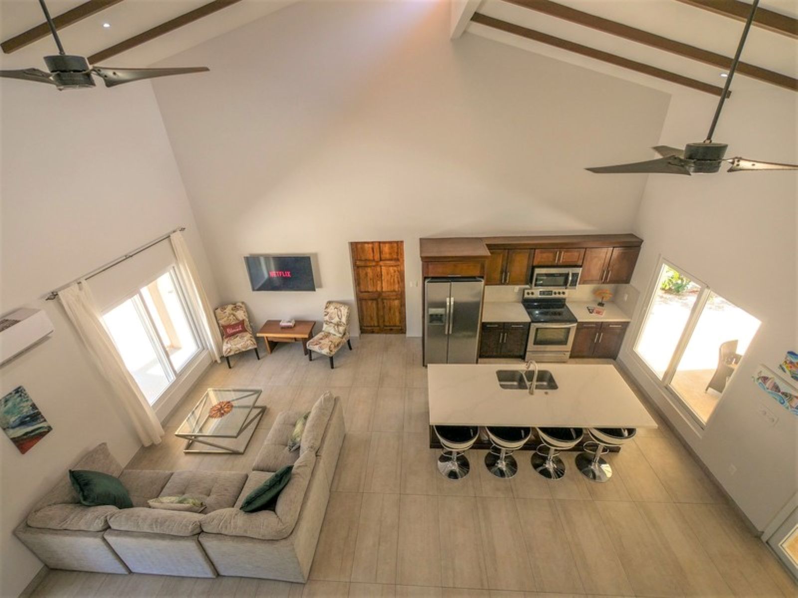Una cocina moderna con una isla central, un área de comedor con un sofá y un televisor montado en la pared.
