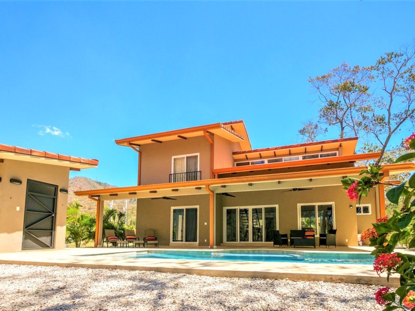 A modern two-story house with a covered patio area and a swimming pool.