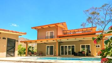 A modern two-story house with a covered patio area and a swimming pool.