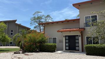 A two-story building with a gravel driveway, a black door, and a small balcony.