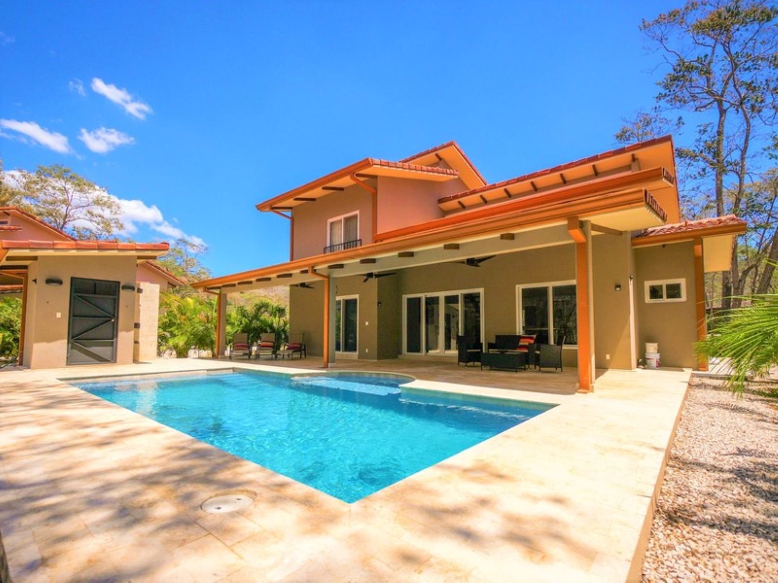 A two-story house with a swimming pool, covered patio, and a view of the surrounding landscape.