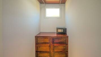 A small room with a wooden dresser, a window, and a ceiling light fixture.