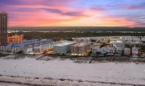 A coastal hotel area with multiple buildings, a parking lot, and a beach. - A Little Peace of the Beach (Orange Beach)