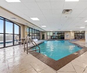 An indoor swimming pool with clear glass walls, a pool ladder, and a tiled floor. - A Little Peace of the Beach (Orange Beach)