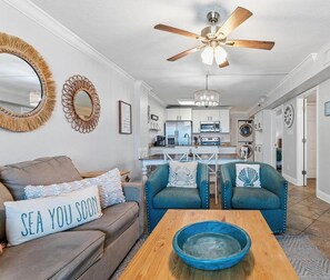 A living room with a sofa, a coffee table, and a dining area with chairs. - A Little Peace of the Beach (Orange Beach)