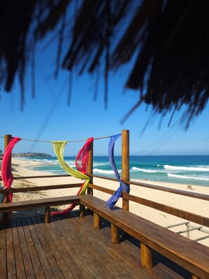 A wooden deck with benches overlooking a beach.