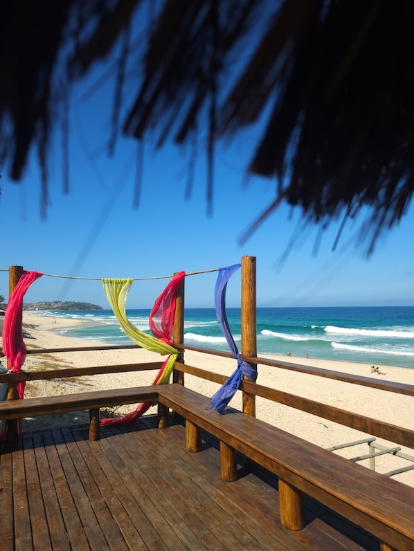 A wooden deck with benches overlooking a beach.