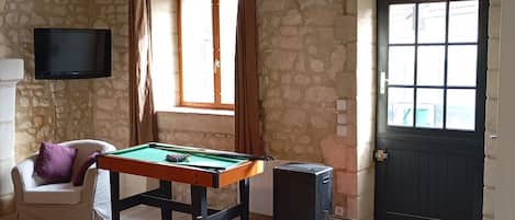 A room with a pool table, a chair, a television, and a door with windows.