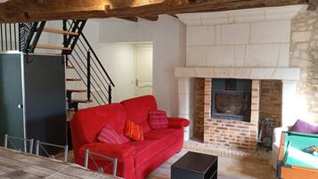 A cozy living room with a red sofa, a fireplace, and a staircase.
