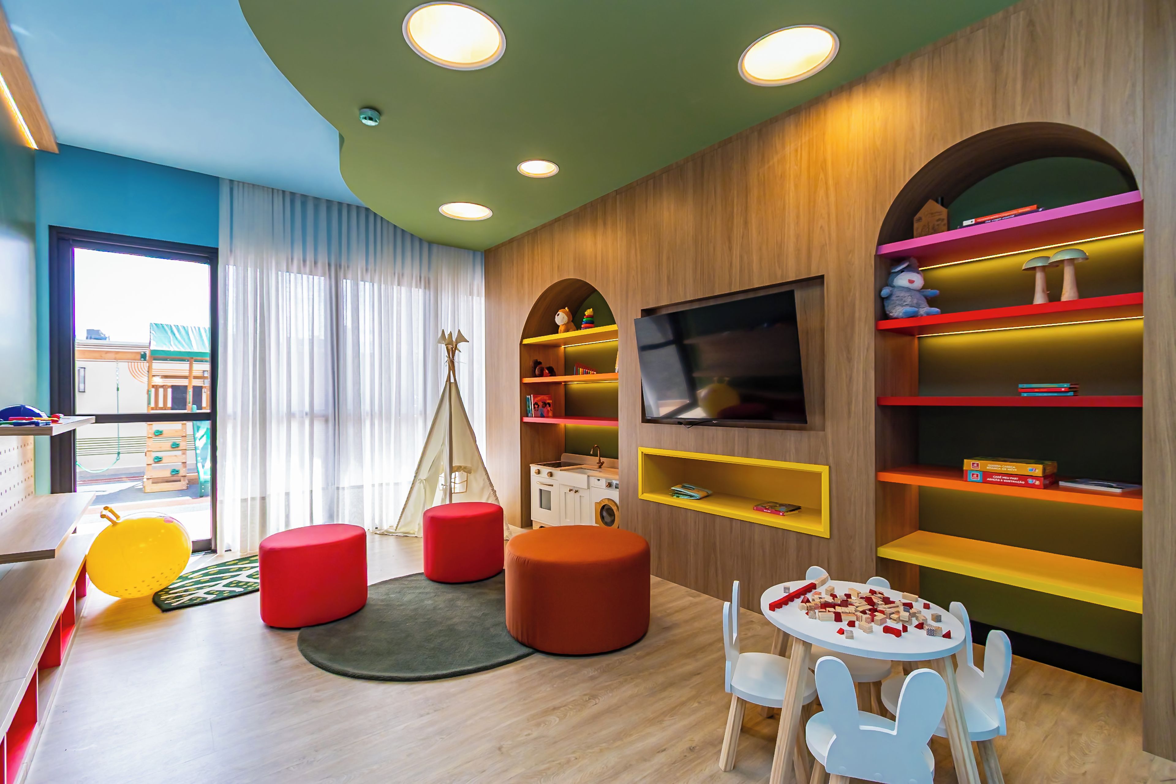 Ein Kinderzimmer mit Fernseher, bunten Regalen und einer Spielzone.