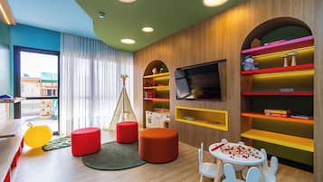 Ein Kinderzimmer mit Fernseher, bunten Regalen und einer Spielzone.
