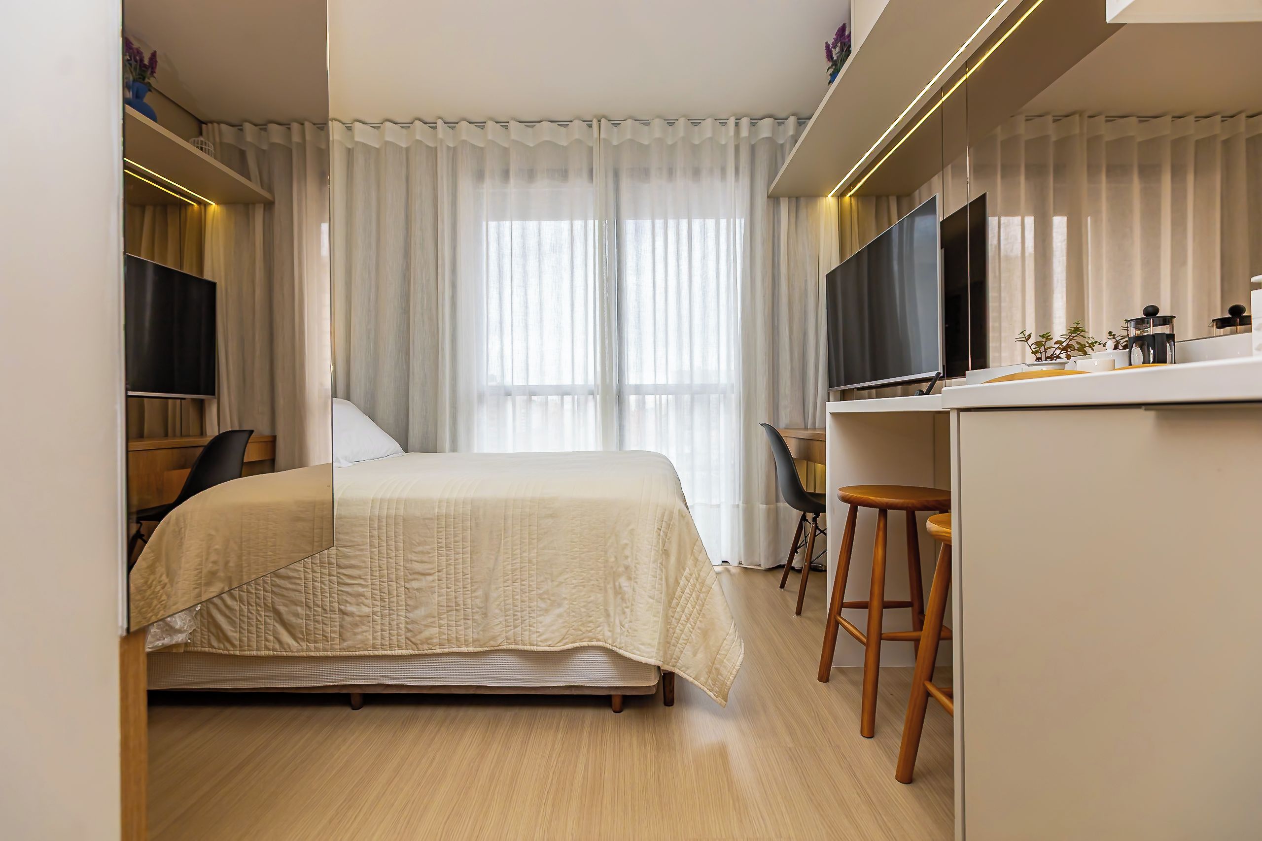 Ein Hotelzimmer mit einem Bett, einem Schreibtisch, einem Sessel, einem Fernseher und einem Fenster mit Vorhängen.