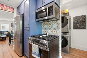 A compact kitchen with a refrigerator, microwave, stove, and washing machine. - Arlington Game Day Suite + Walk to AT&T & Globe Life (Arlington)