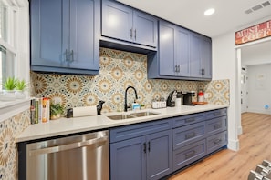 A modern kitchen with blue cabinets, a stainless steel dishwasher, and a patterned backsplash. - Arlington Game Day Suite + Walk to AT&T & Globe Life (Arlington)