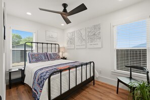 A bedroom with a bed, a desk, a chair, a ceiling fan, and three wall maps. - Arlington Game Day Suite + Walk to AT&T & Globe Life (Arlington)
