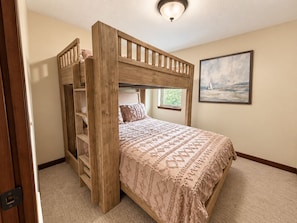 Quarto com beliche, janela, quadro na parede e porta.