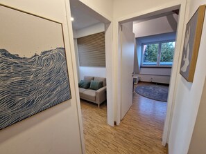 Ein Flur mit Holzboden, einer Couch mit Kissen und einem großen abstrakten Gemälde an der Wand.