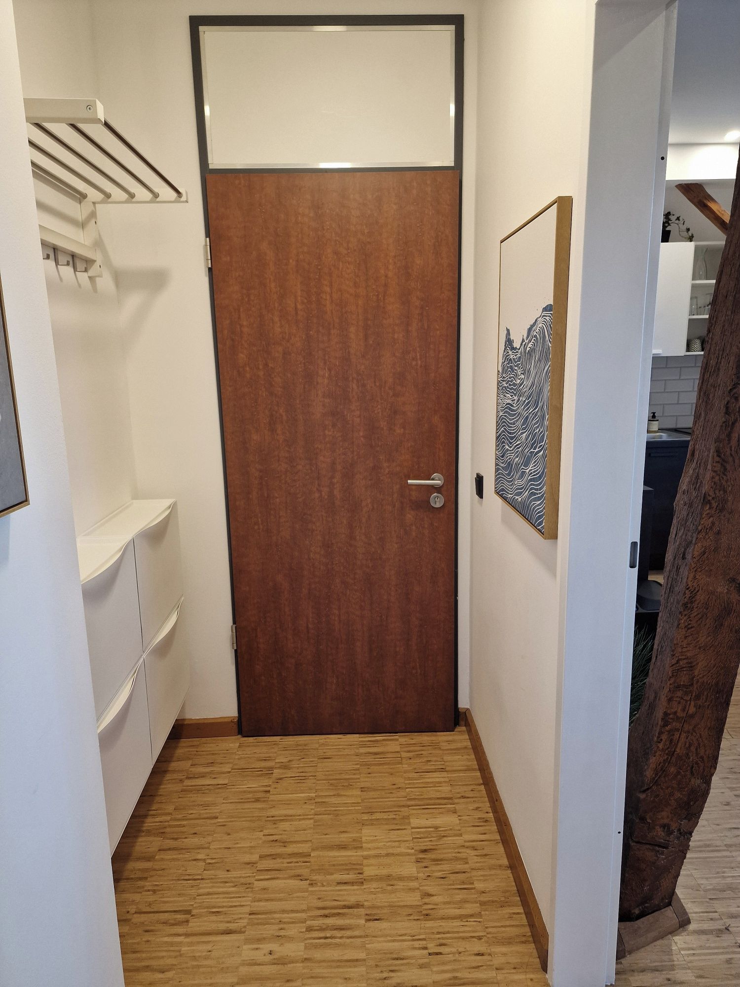 Ein Flur mit einer Holztür, einer weißen Wand und einem Holzboden.