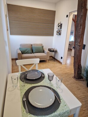 Ein Essbereich mit einem Tisch für zwei Personen, einer Couch und einem kleinen Tisch mit einem Radio.
