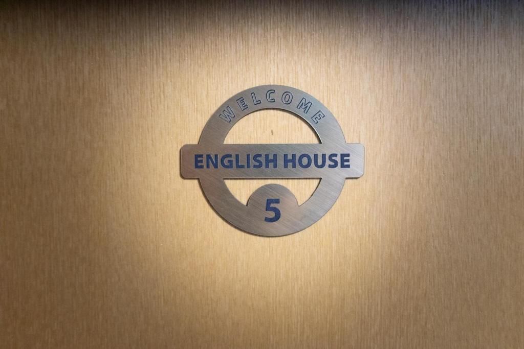 Un cartel de bienvenida con 'ENGLISH HOUSE 5' sobre una superficie de madera.