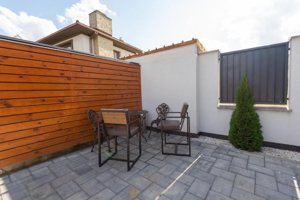 A patio area with a wooden fence, two metal chairs, a small table, and a potted plant.
