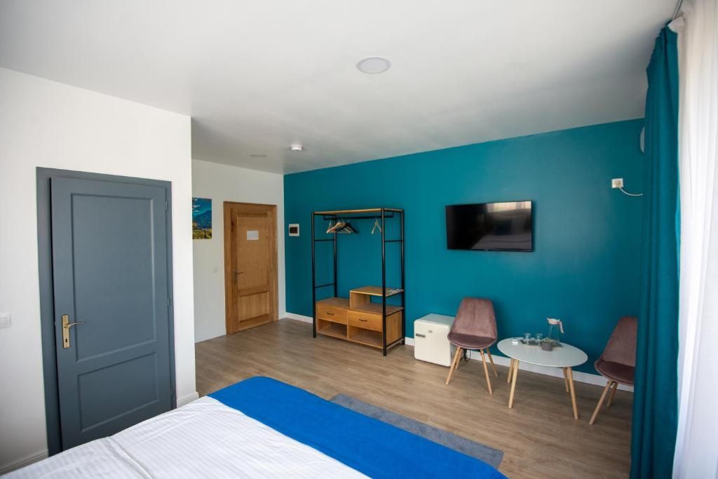 A hotel room with a bed, a desk, two chairs, a TV, and a wardrobe.