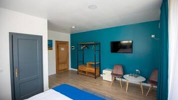 A hotel room with a bed, a desk, two chairs, a TV, and a wardrobe.