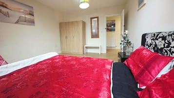 Ett sovrum med en stor säng, en garderob, en bänk och utsikt över omgivningen.
