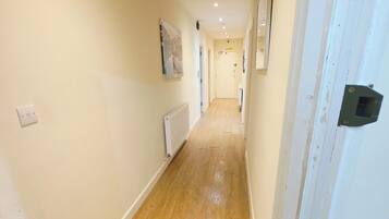 A hallway with wooden flooring, white walls, and a door with a black handle.