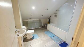 A bathroom with a toilet, bidet, bathtub, and a shower area.
