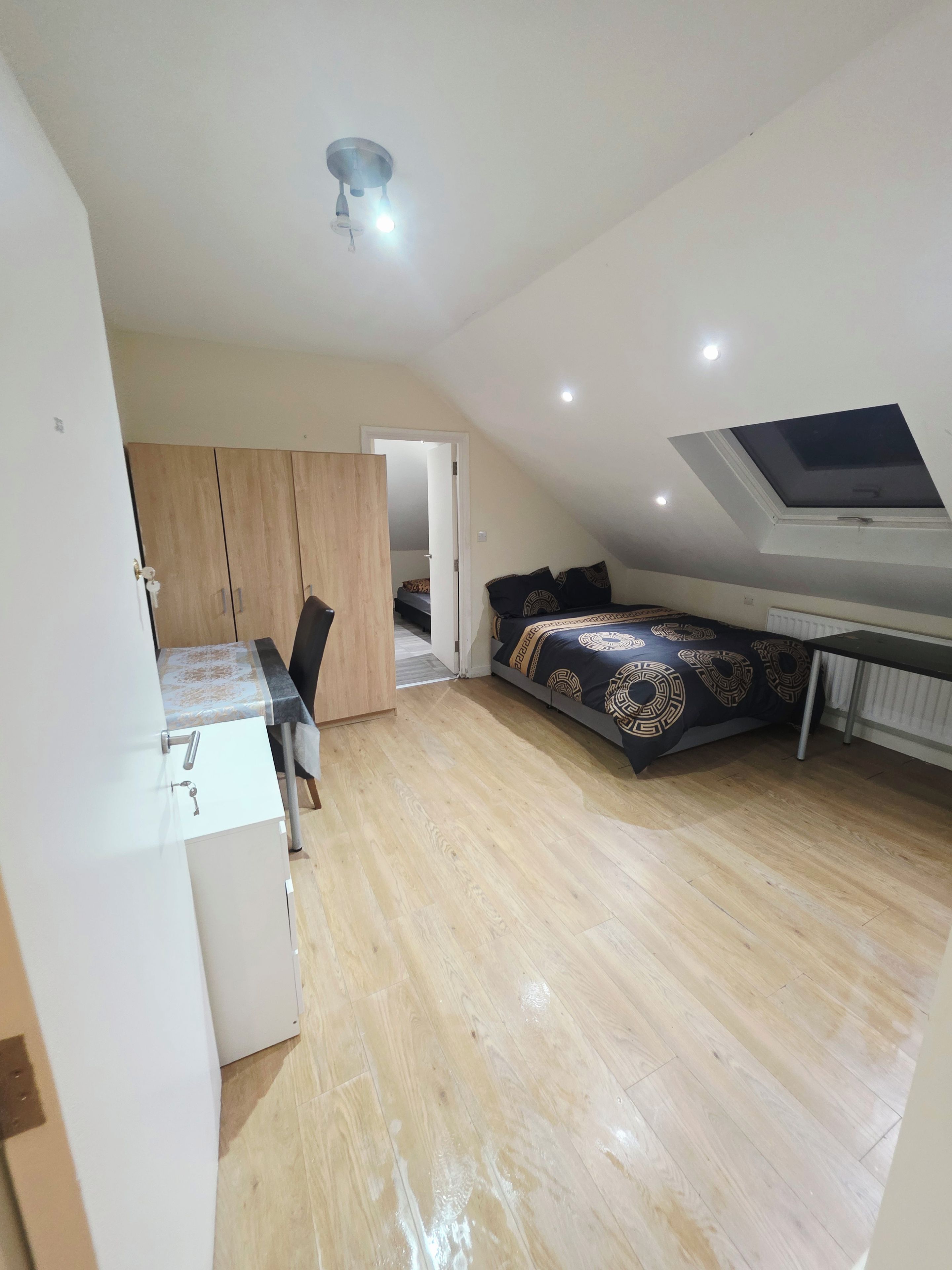A compact bedroom with a bed, a desk, and a wardrobe.