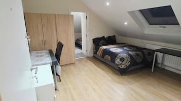 A compact bedroom with a bed, a desk, and a wardrobe.