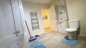 A bathroom with a shower, toilet, sink, and a towel rack.