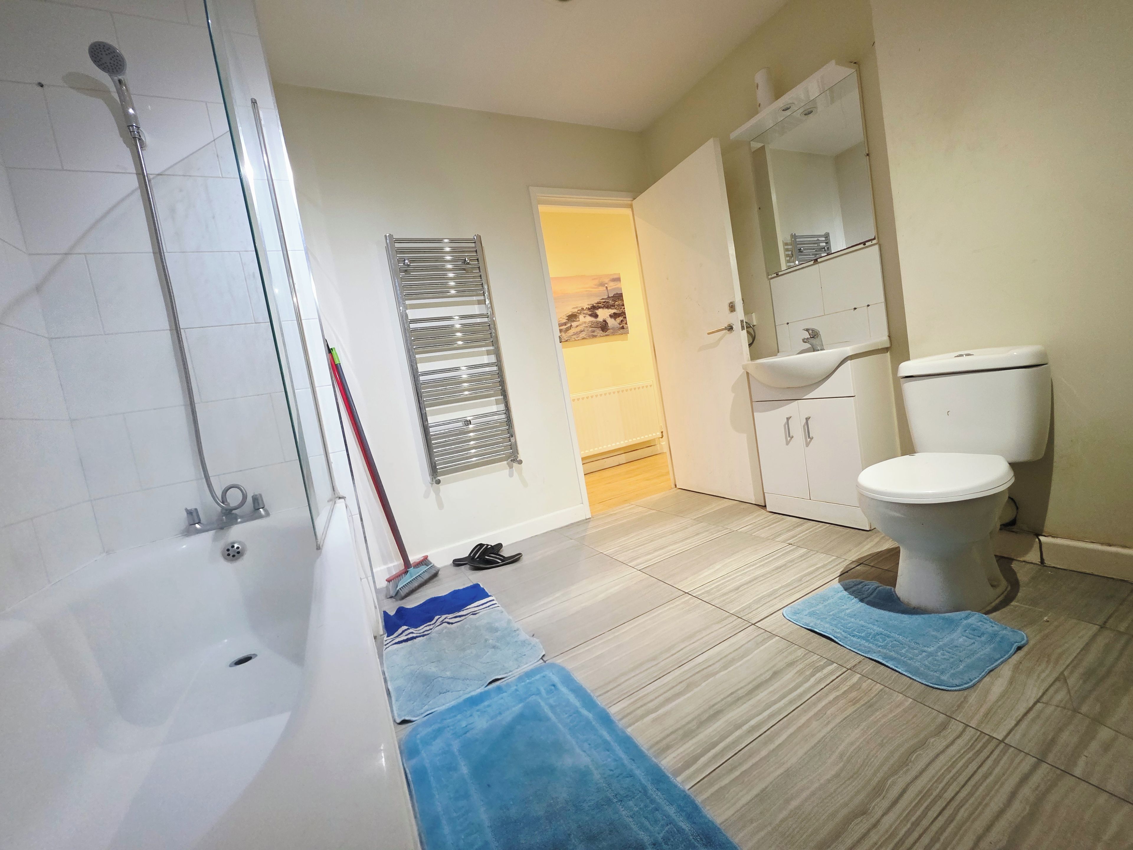 A bathroom with a bathtub, a toilet, a showerhead, a towel rack, and a mirror.