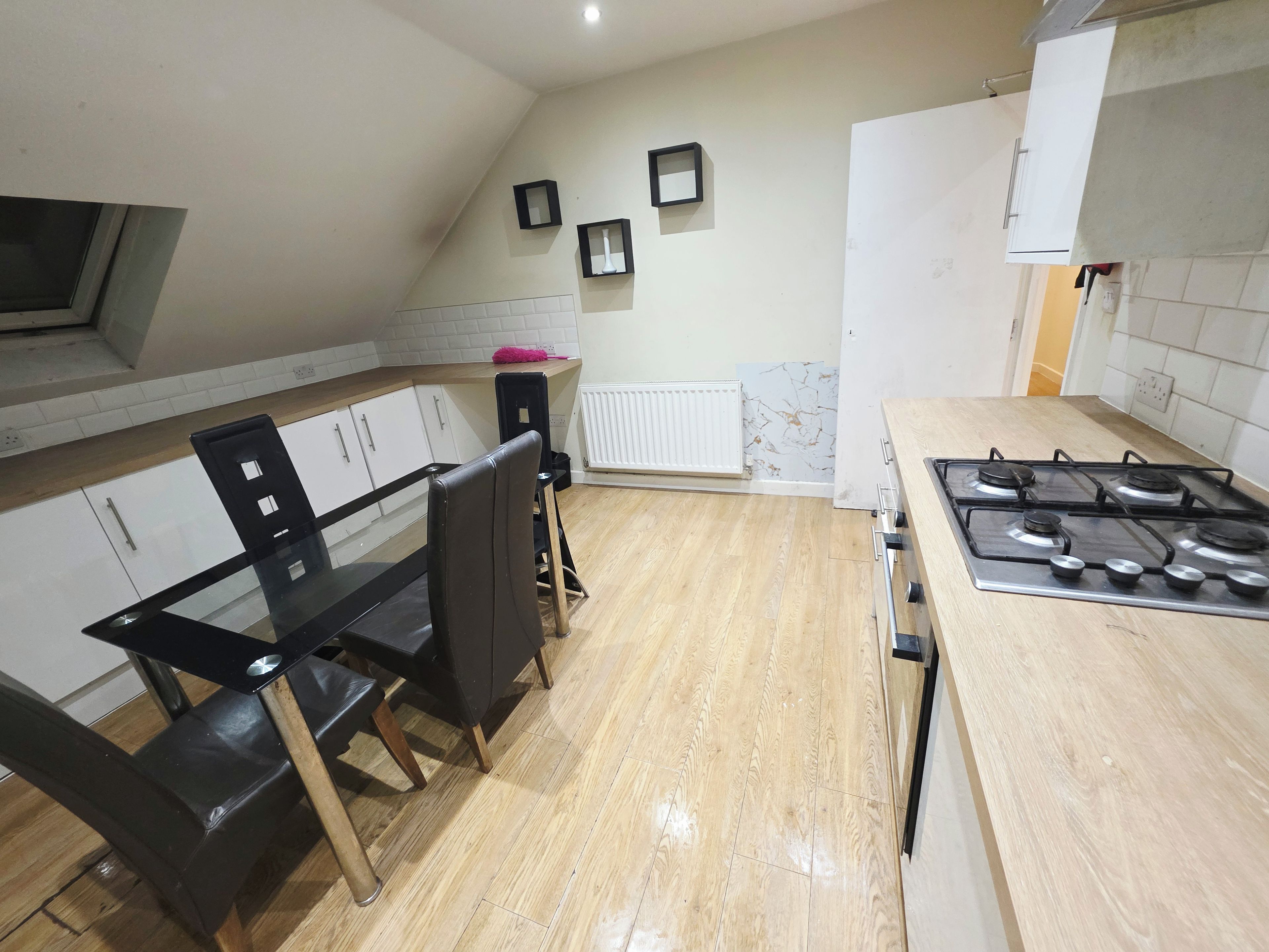 A kitchen with a dining table, chairs, a stove, and cabinets.