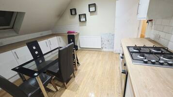 A kitchen with a dining table, chairs, a stove, and cabinets.