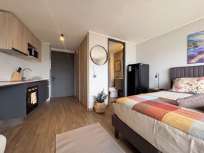 Ein modernes Schlafzimmer mit Bett, Nachttisch, Kommode, Spiegel und einem Bild an der Wand.