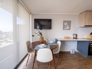 Eine moderne Küche mit Essbereich, einem flachbildfernseher an der Wand und Blick auf die Stadt durch das Fenster.