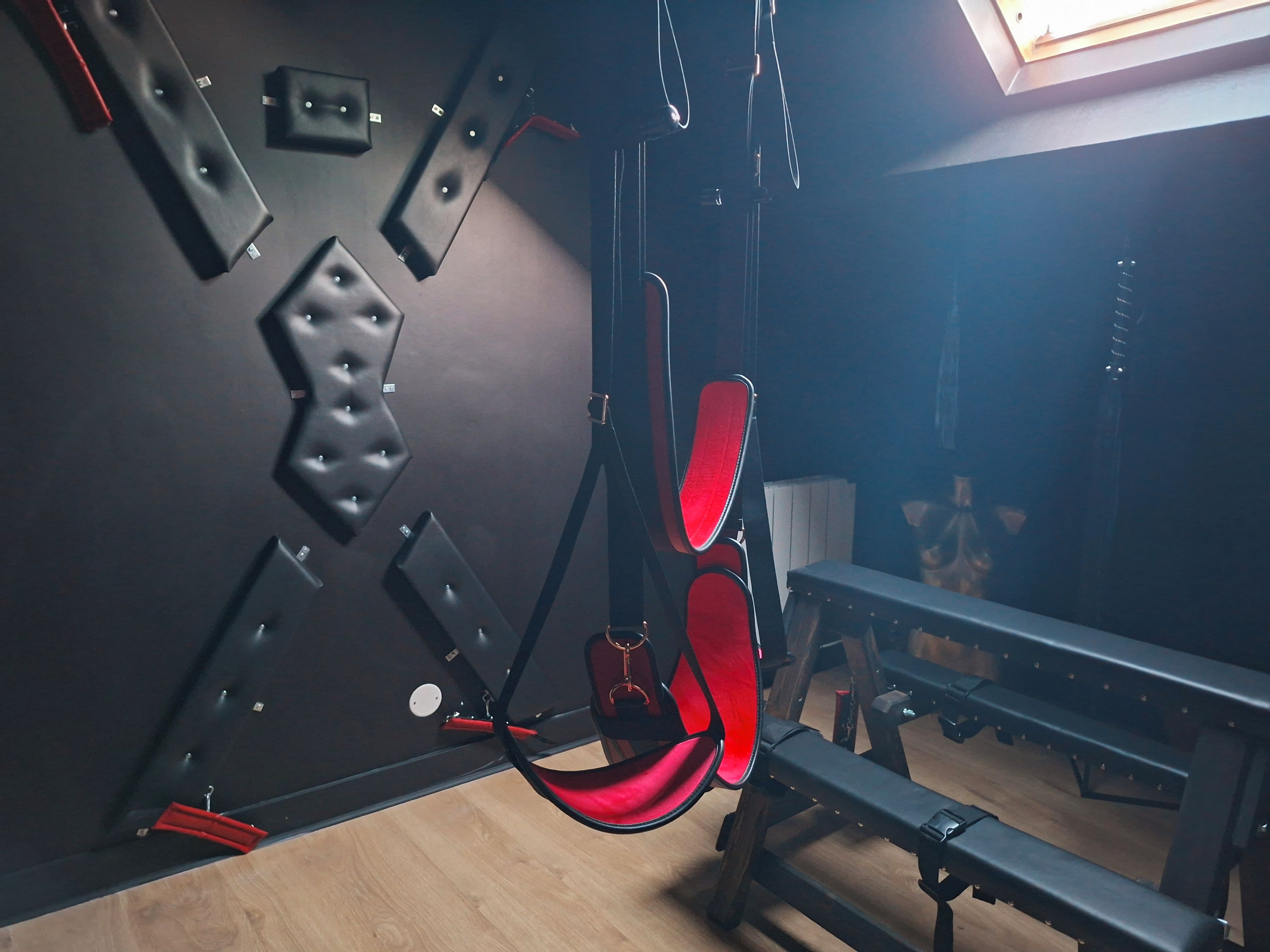 A gym with exercise equipment, a bench, and a wall-mounted rack.