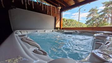 Un bain à remous avec un plafond en bois et une vue sur les arbres à l’extérieur.