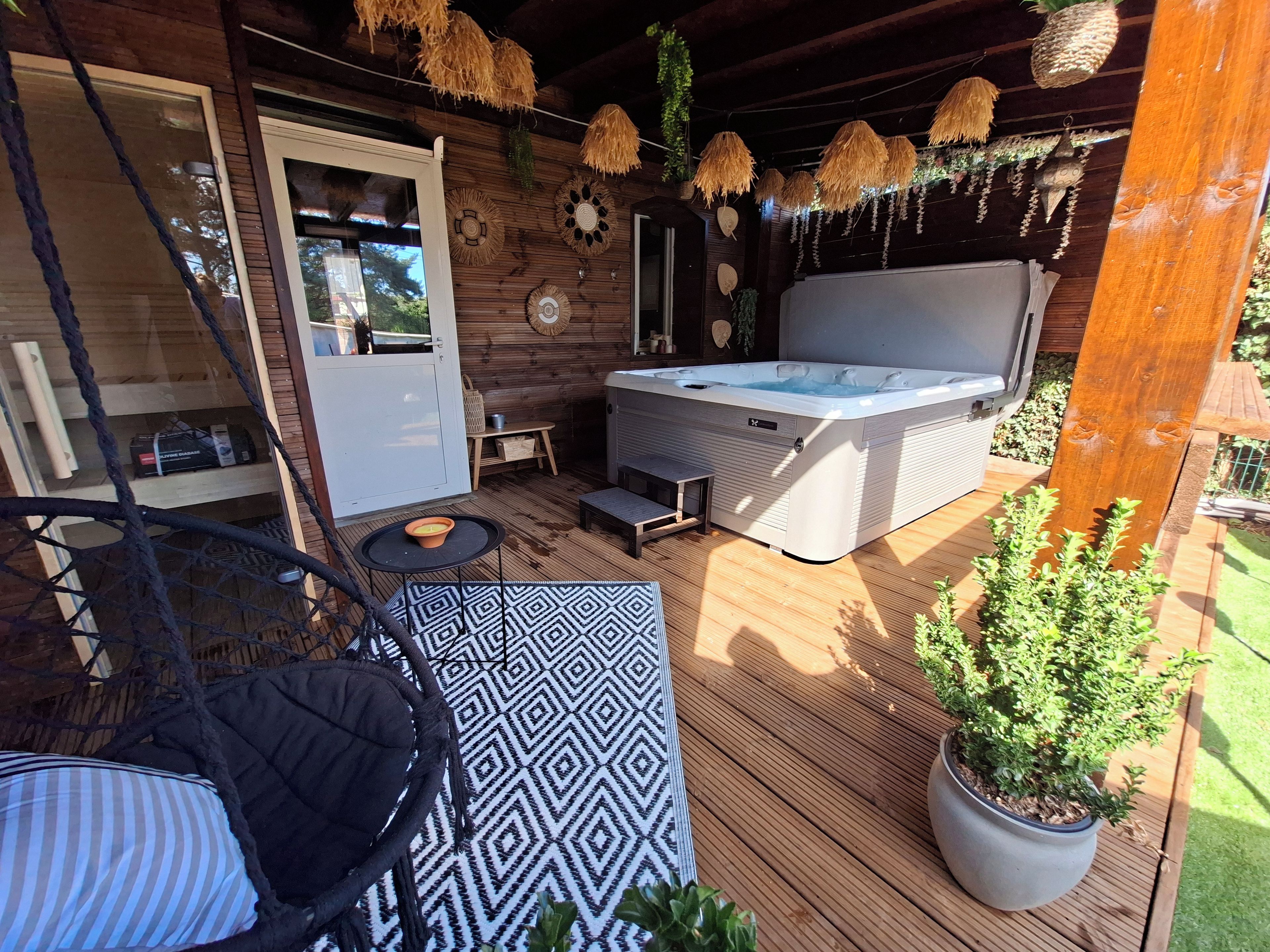 Eine Holzterrasse mit Whirlpool, einer Hängematte und einem Blumentopf.