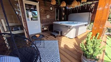 Eine Holzterrasse mit Whirlpool, einer Hängematte und einem Blumentopf.